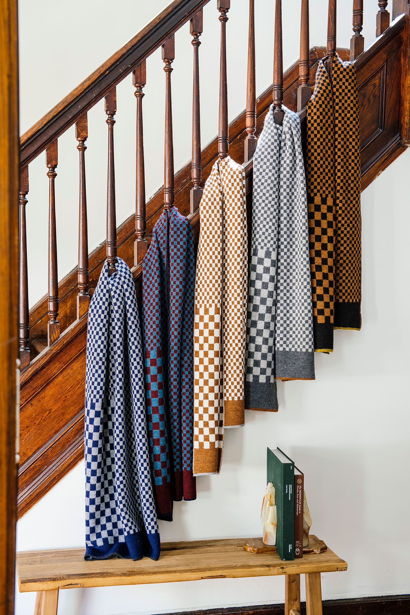 Paris West's collection of 100% royal alpaca Checker Scarves, hanging from a staircase banister