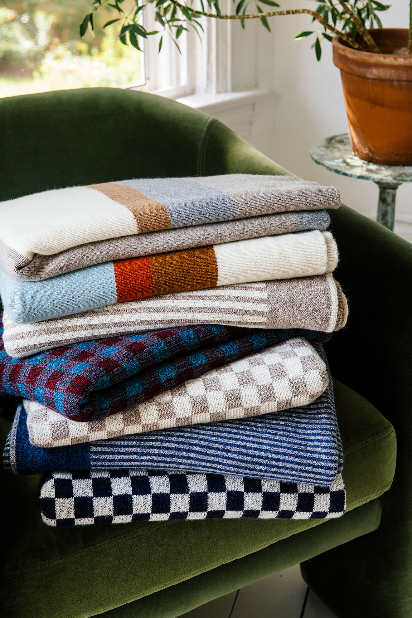 Stack of Paris West throws on green chair